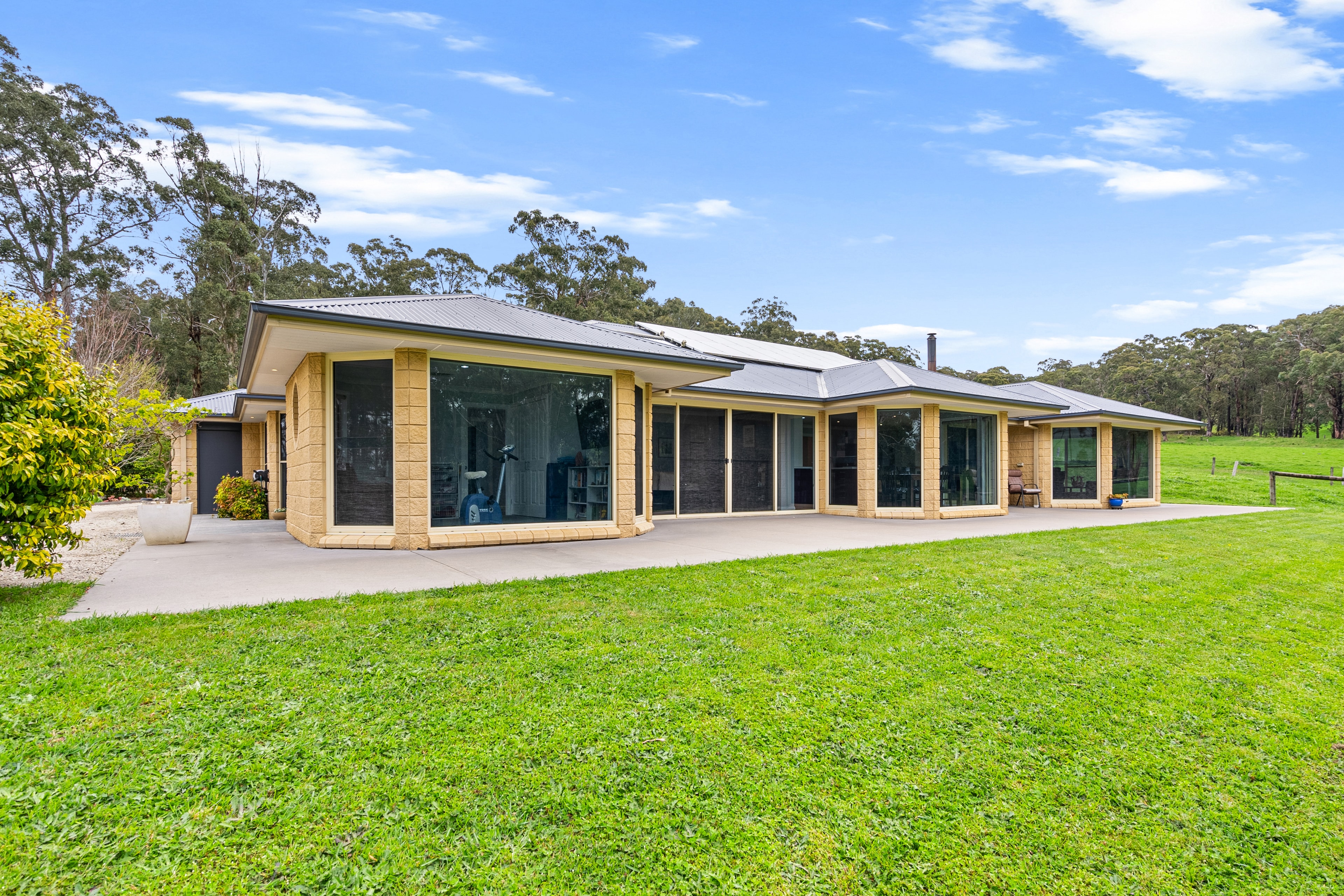 Acreage home exterior with expansive glass facade and green lawns