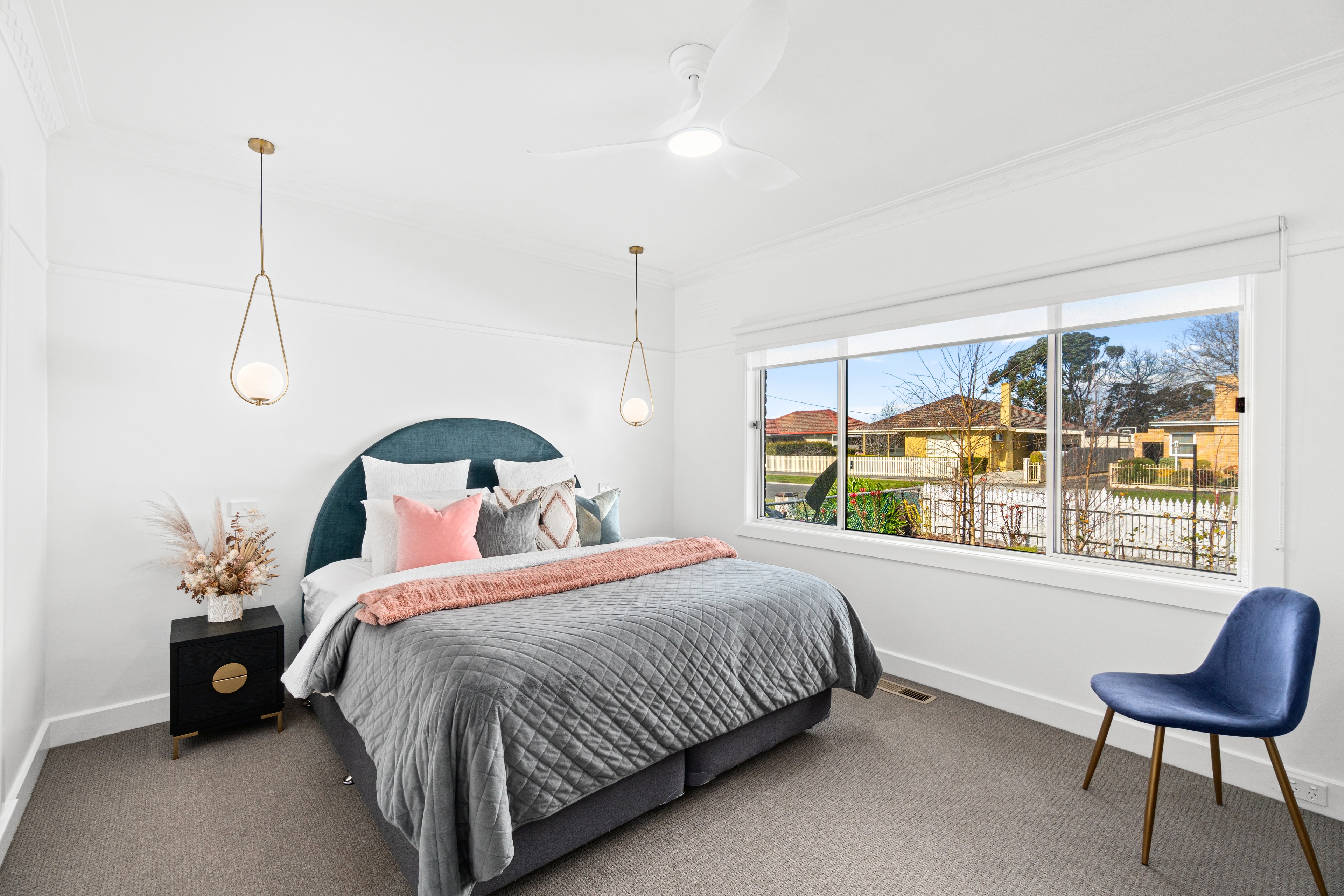Modern bedroom with teal headboard and pendant lights