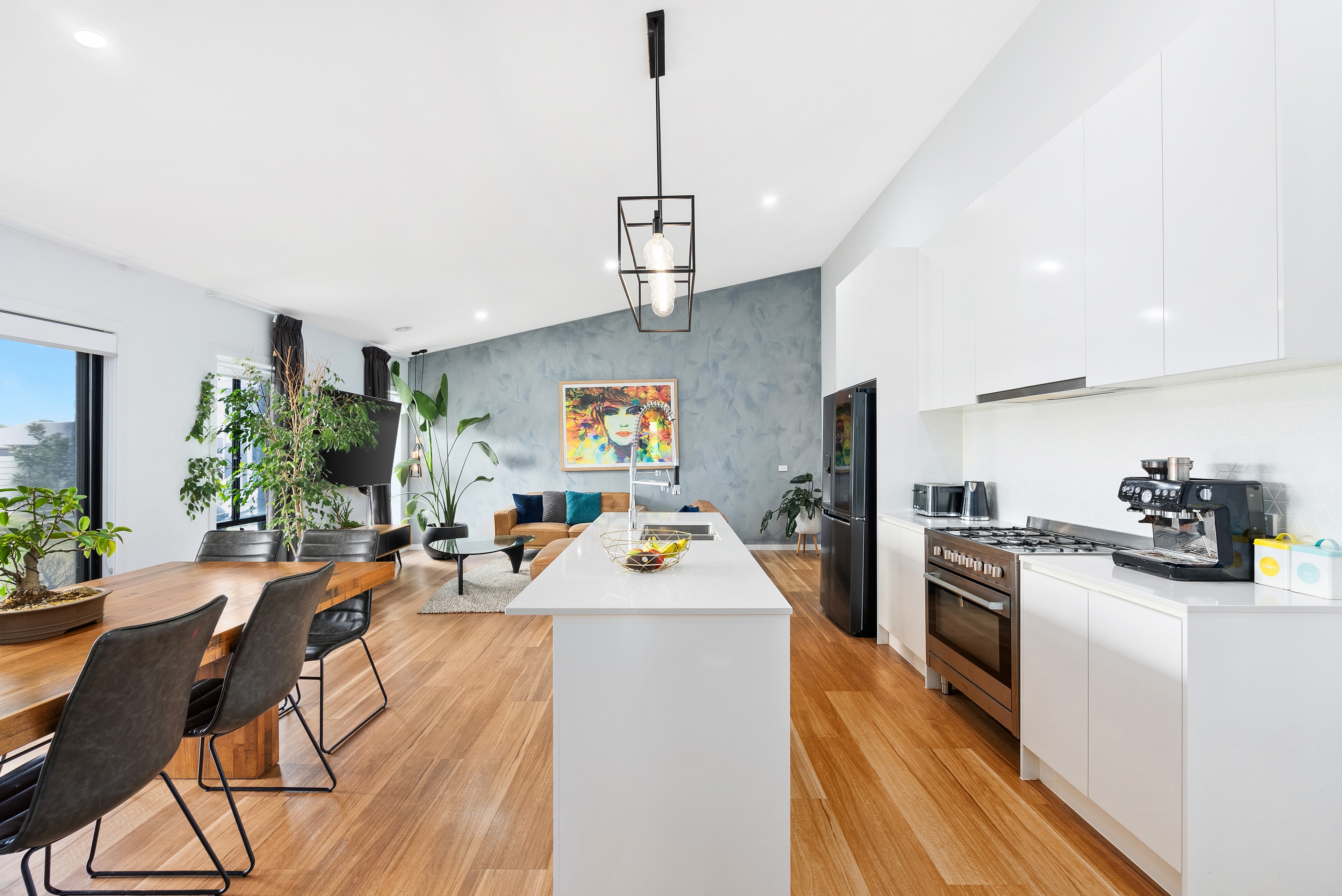 Open-plan kitchen and living with timber floors and colourful artwork