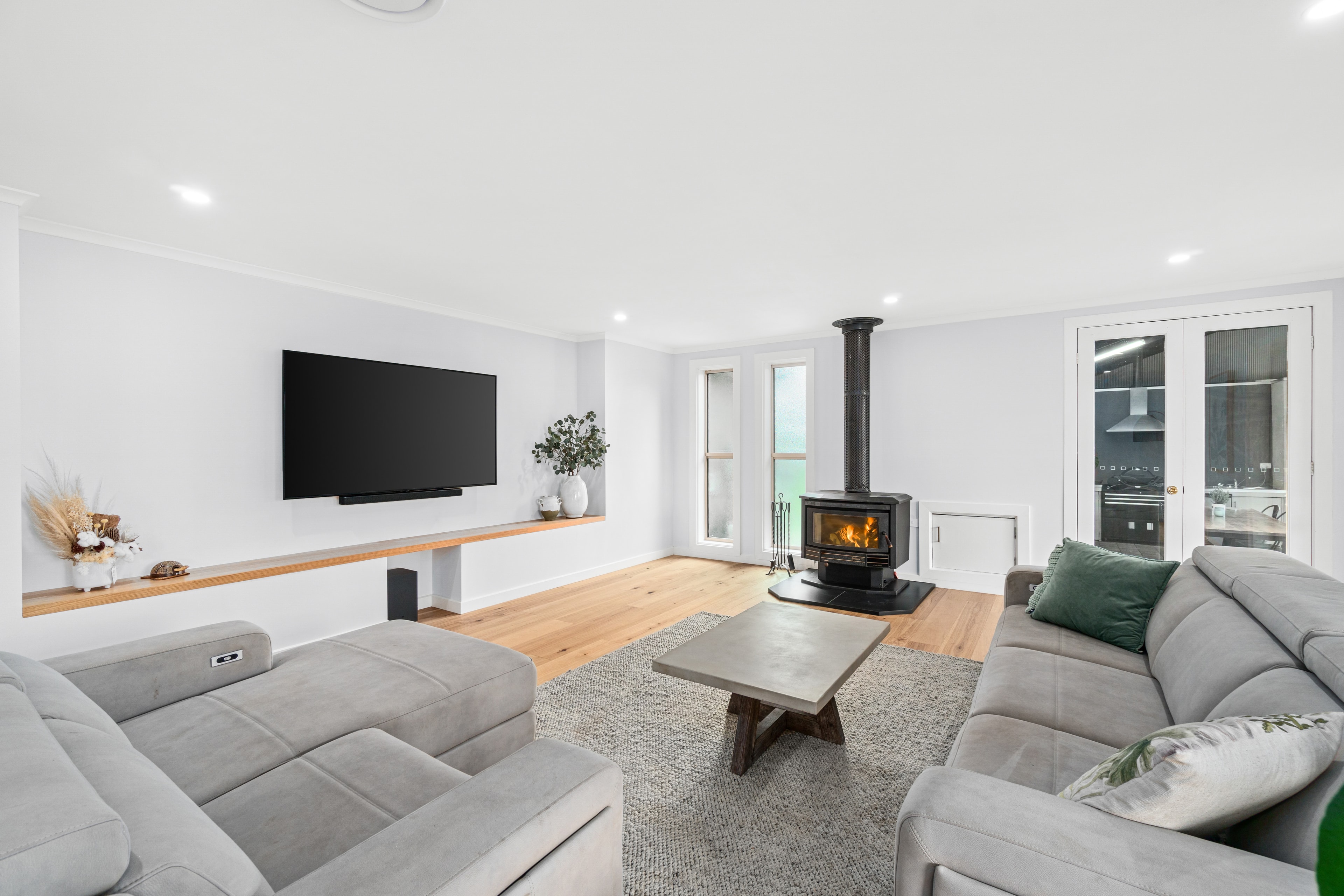 Bright lounge room with wood fire and wall-mounted TV