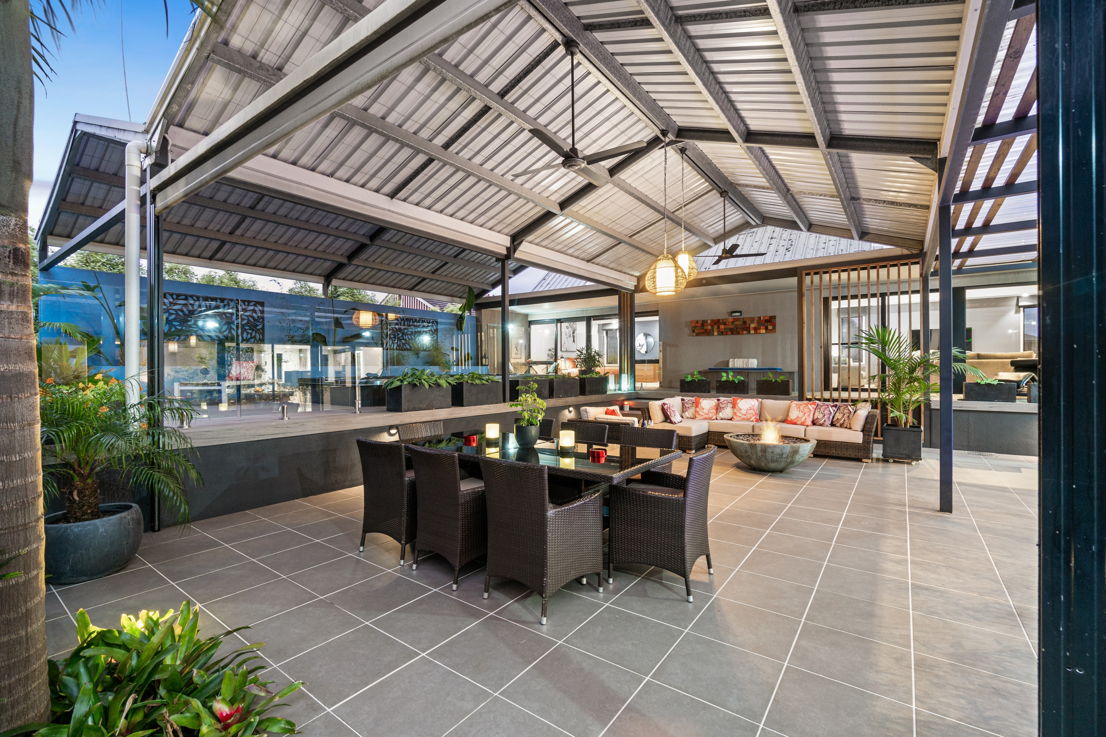 Covered outdoor entertaining area with rattan furniture and tropical plants