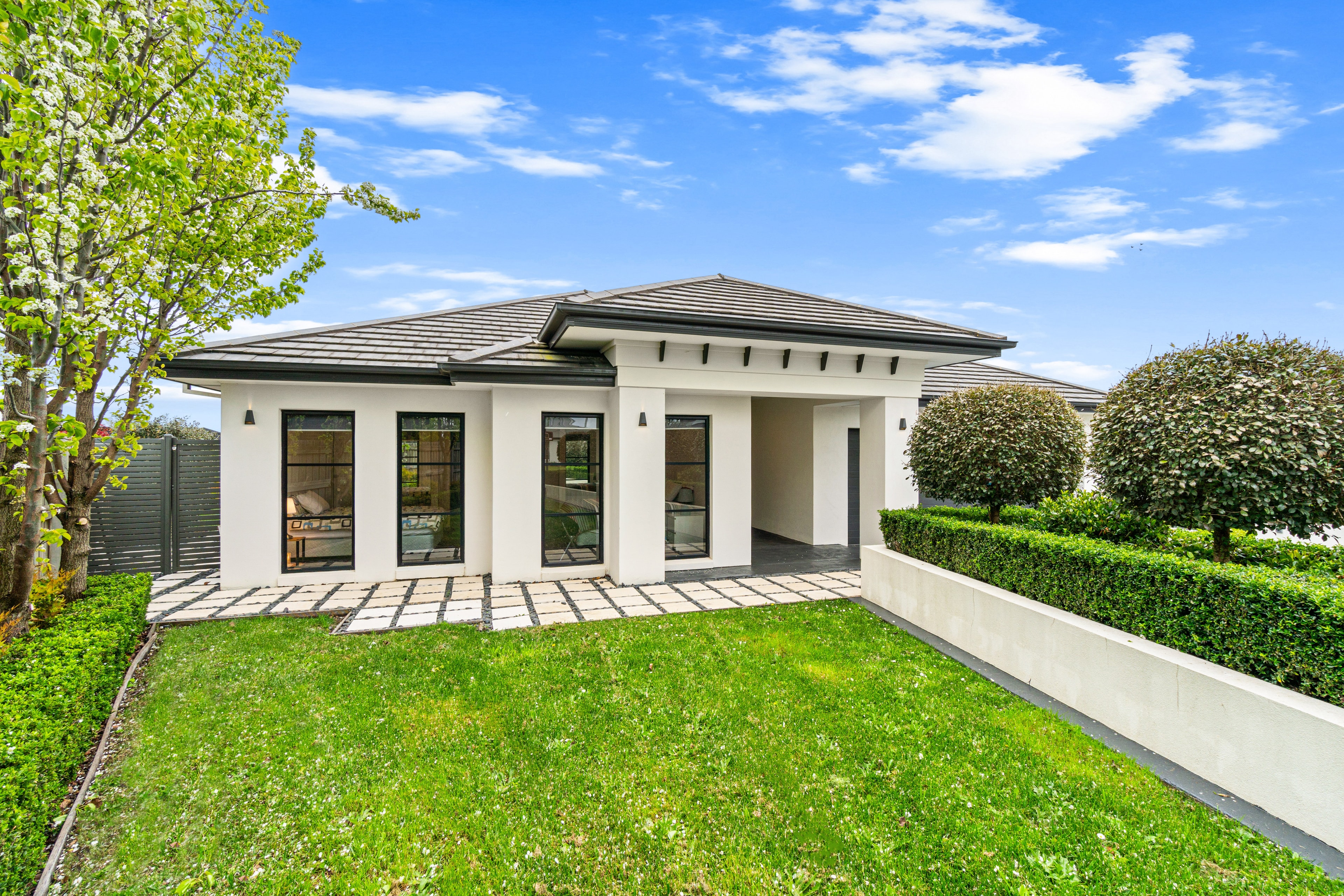 Contemporary white facade home with manicured hedges